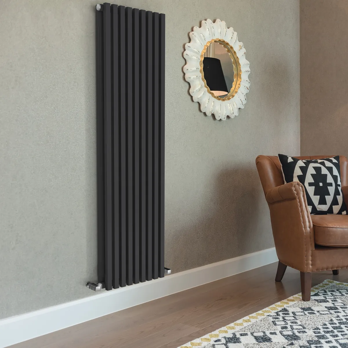 Designradiator Vertica D Bi in antraciet in een woonkamer met fauteuil en spiegel